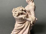 figurine of a woman with a basket of flowers on a table