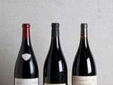 three bottles of wine are lined up on a wooden table