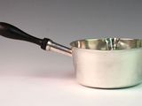 a silver saucepan with a wooden handle on a white table