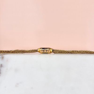 un gros plan d'un bracelet en or posé sur une surface en marbre