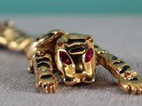 a close up of a gold and red animal brooch