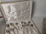silverware in a silver case sitting on a table next to a vase