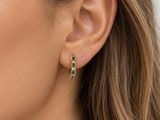 un gros plan sur une femme portant une paire de boucles d'oreilles vertes