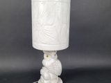 a white table lamp with a white shade on top of it