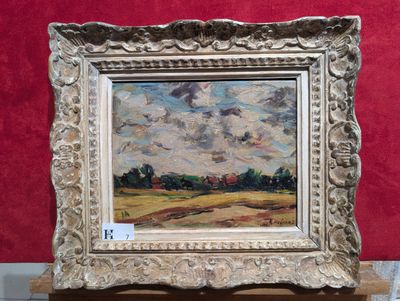 une peinture à l'huile représentant un paysage, dans un cadre argenté, posée sur une table
