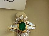 an image of a ring with a green stone surrounded by diamonds
