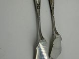 pair of silver spoons sitting on top of a white table