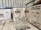 Plusieurs verres à vin vides sont posés sur une table devant des caisses de bière