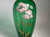 un vase vert sur lequel sont peintes des fleurs roses
