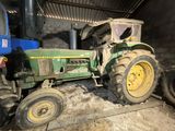 a green tractor that is parked in a barn