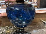 a blue vase sitting on a table with a lamp on top of it