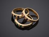 three gold rings with different colored stones on a black surface