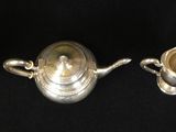three silver teapots are lined up on a black background