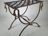 an antique wrought iron table with brass legs and a glass top
