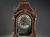 une horloge rouge et dorée ornée de chiffres romains bleus