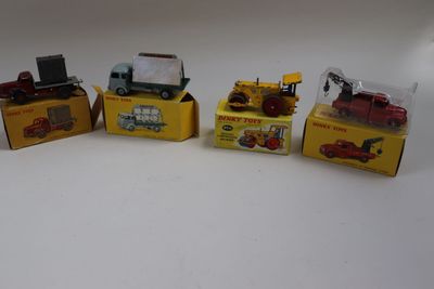 Quatre camions miniatures sont alignés les uns à côté des autres sur une surface blanche