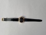 gros plan d'une montre sur une surface blanche avec un bracelet noir
