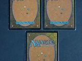 three magic the gathering cards are sitting on top of each other