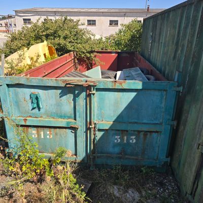 a blue dumpster sitting in a yard next to a wooden fence
