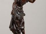 an antique bronze statue of a woman with a basket on her head
