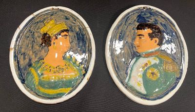une paire de portraits en céramique représentant un homme et une femme