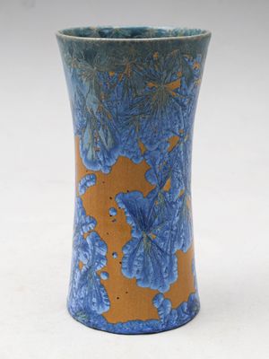 un vase bleu et orange posé sur une surface blanche