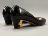 a pair of black pumps with gold hardware on the heel