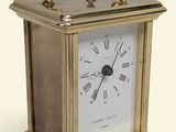 une petite horloge en laiton avec des chiffres romains