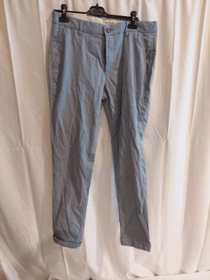 a pair of blue pants hanging on a hanger on a white curtain