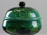 a green bowl with a black lid sitting on a table