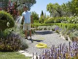 a man that is standing in the garden with a hose