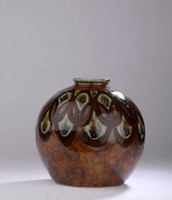 un vase marron et vert posé sur une surface blanche