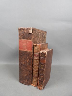 two old books sitting on top of each other on a table