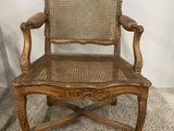 an old wooden chair with wicker seat on carpeted area