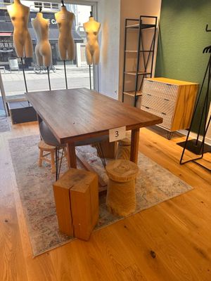 une table en bois au milieu d'une pièce, avec des mannequins en arrière-plan