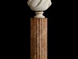 marble bust of a woman on a pedestal against a black background
