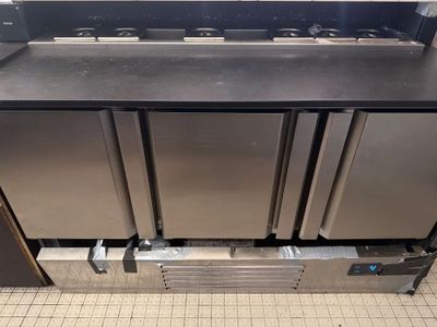 trois réfrigérateurs en acier inoxydable posés sur un plan de travail dans une cuisine