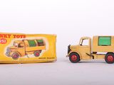 yellow toy truck next to a yellow box on a white surface