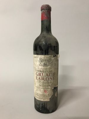 une vieille bouteille de vin posée sur une table blanche