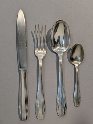 cinq cuillères en argent, une fourchette et un couteau posés sur une table