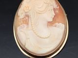 un gros plan sur une broche représentant une femme en robe