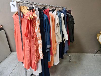 beaucoup de vêtements suspendus à une étagère dans une pièce