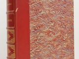un vieux livre à la couverture rouge posé sur une table blanche
