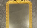miroir à cadre doré orné d'un motif floral dans sa partie supérieure