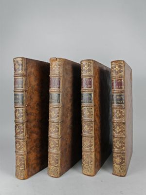 three old books are lined up in a row on a white surface