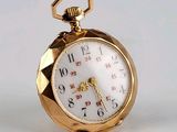 une montre de poche en or posée sur une surface blanche