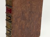 an old book with a brown cover sitting on top of a white surface