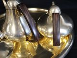 a silver tea pot and two silver spoons on a silver tray