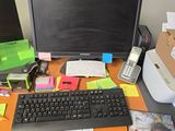 un bureau sur lequel se trouvent un ordinateur, un clavier, un téléphone et d'autres objets