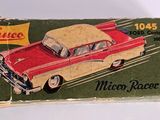 an old red and yellow toy car sitting on top of a green box